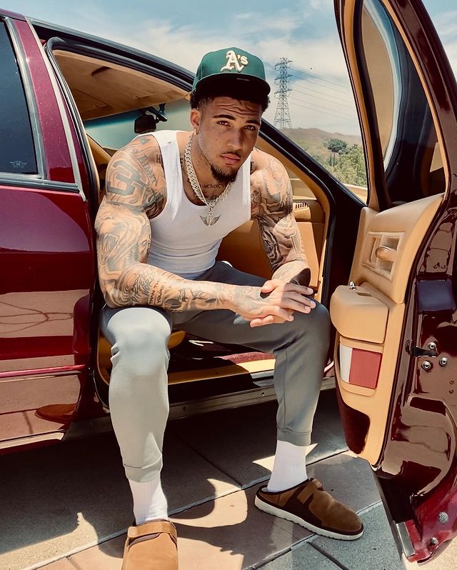 LiAngelo Ball sitting in his car in a green car and white half dress.